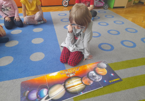 Dziewczynka ogląda planety przez okulary 3D.