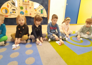 Dzieci słuchają piosenki o bałwanku i wskazuja palcem odpowiednie elementy stroju.