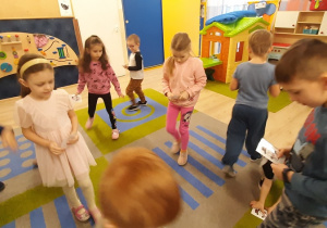 Dzieci spacerują po sali i losują obrazek z bałwankiem.