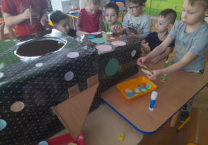 Dzieci przyklejają kółka na rakietę.