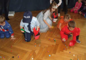 Dzieci zbierają pompony za pomocą szczypiec.