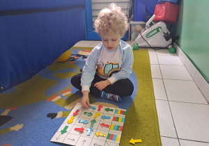 Chłopiec koduje siedząc na dywanie.