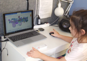 Dziewczynka tworzy obrazek w programie na laptopie.
