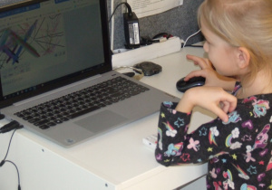 Dziewczynka tworzy obrazek w programie na laptopie.