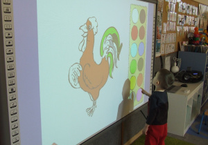 Chłopiec koloruje ilustrację w programie.