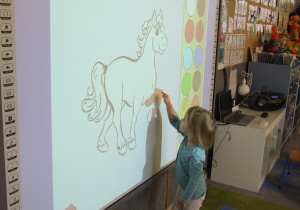 Dziewczynka koloruje ilustrację w programie.