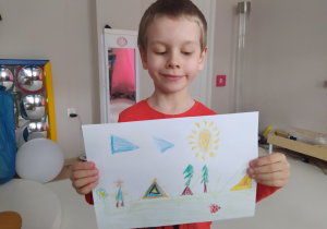 Chłopiec prezentuje rysunek trójkątnej krainy.
