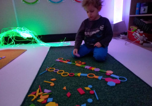 chłopiec układa z mozaiki geometrycznej.