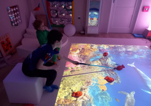 Dzieci łowią ryby na podłodze interaktywnej.