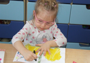 Dziewczynka rysuje wymyślone elementy do istniejącej plamy z farby.