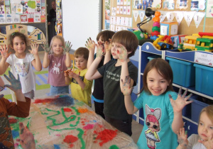 Dzieci pokazują kolorowe dłonie.