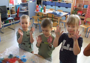 Dzieci pokazują kolorowe dłonie.
