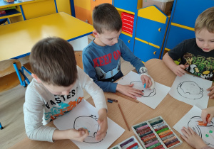 Dzieci przy stolikach dokańczają swój portret.
