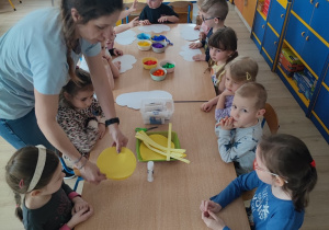 Nauczycielka rozdaje dzieciom żółte kołka.
