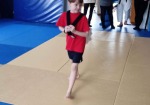 Chłopiec niesie strój judo na plecach.