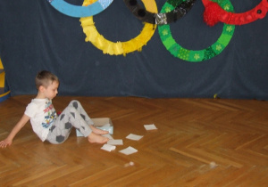 Chłopiec chwyta papier palcami od nóg.
