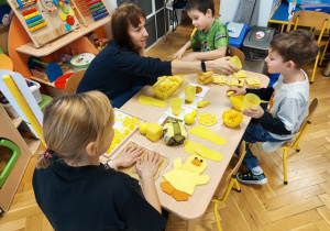 Dzieci bawią się przy stolikach z różnego rodzaju pomocami sensorycznymi.