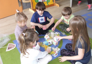 Dzieci budują domek z papierowych klocków wypełnionych siankiem.