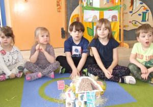 Dzieci prezentują domek z klocków papierowych wypełnionych siankiem.