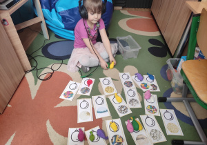 Dziewczynka rozwiązuje zagadki sensoryczne ukryte w balonach.