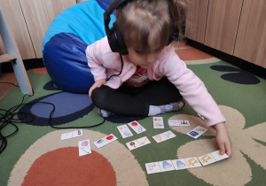 Dziewczynka układa domino obrazkowe.