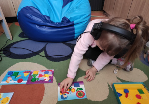 Dziewczynka układa kolorowe figury geometryczne.
