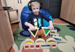 Chłopiec prezentuje swoją budowlę z klocków.