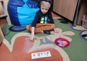 Chłopiec układa obrazek z figur geometrycznych według wzoru.