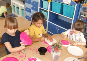 Dzieci malują farbami papierowe talerze.