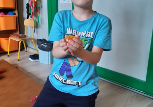 Chłopiec siedzi na materacu i układa owoc.
