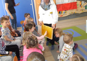 Chłopiec prezentuje dzieciom plaster miodu.