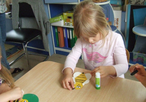 Dziewczynka ozdabia pszczołę zrobioną z origami z kół.