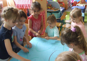 Dzieci malują łąkę na dużym arkuszu papieru.