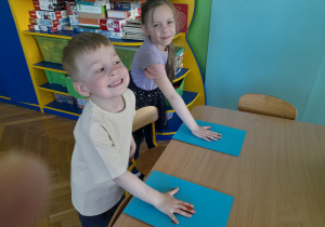 Dzieci odbijają swoją dłoń na kartce papieru.