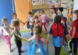 Dzieci przebrane za owady tańczą w kole.