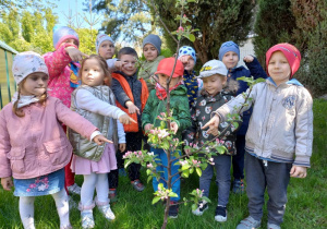 Dzieci stoją przy drzewku jabłoni 9.05.2023.