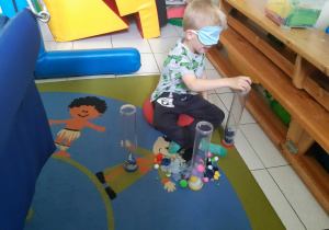 Chłopiec z opaską na oczach segreguje przedmioty.