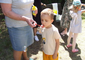 Chłopiec puszcza bańki mydlane.