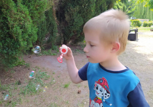 Chłopiec robi bańki mydlane.