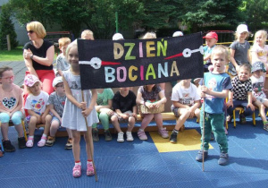 Dzieci trzymają transparent z napisem "Dzień Bociana".