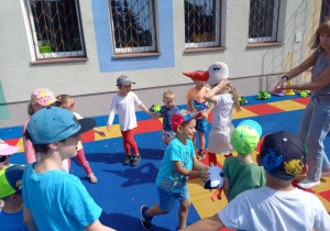 Dzieci bawią się na tarasie z maskotkami bocianów.