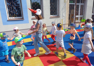 Dzieci bawią się na tarasie z maskotkami bocianów.