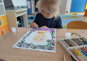 Dziewczynka koloruje pastelami portret mamy.