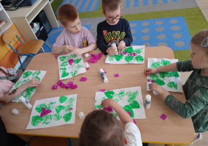 Dzieci z bibuły formują kwiaty bzu i przyklejają na kartce.