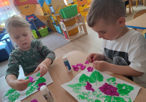 Dzieci z bibuły formuja kwiaty bzu.
