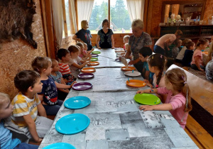 Dzieci siedzą przy stole na warsztatach z pieczenia chleba.