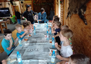 Dzieci jedzą kiełbaski z grila.