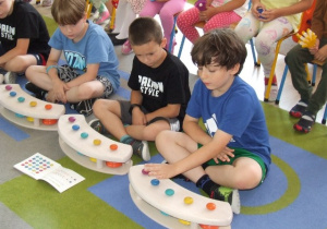 Dzieci grają na kolorowych dzwonkach i kołatkach.