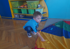 Chłopiec układa kropki na odpowiedni kolor na chuście.