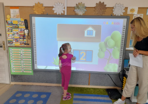 Dziewczynka wskazuje cyfrę na ekranie.
